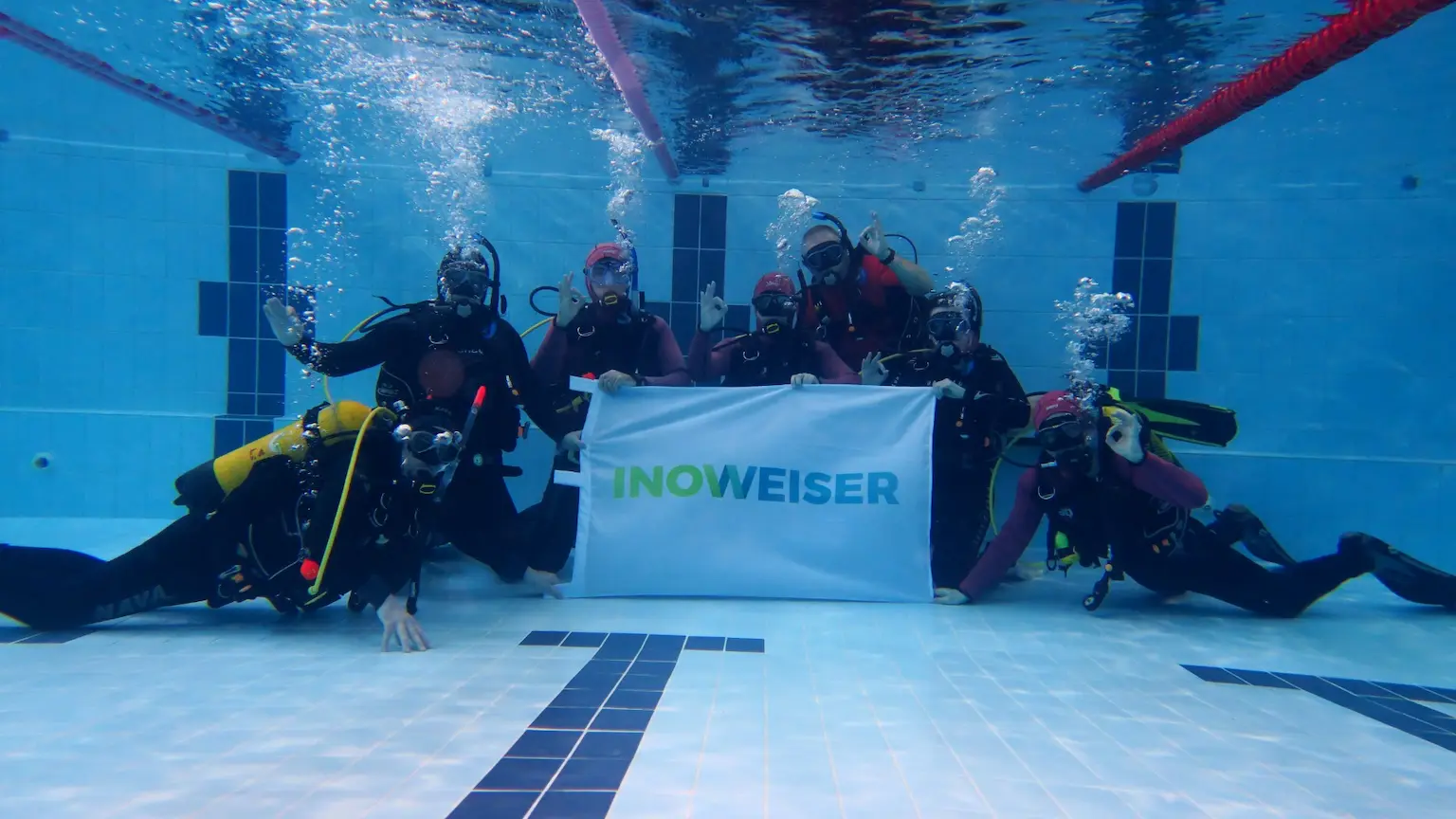 underwater divers holding company banner pool